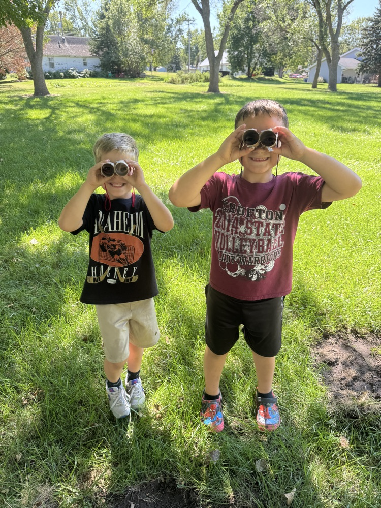 Kindergarteners using their binoculars to help them find living things at the park