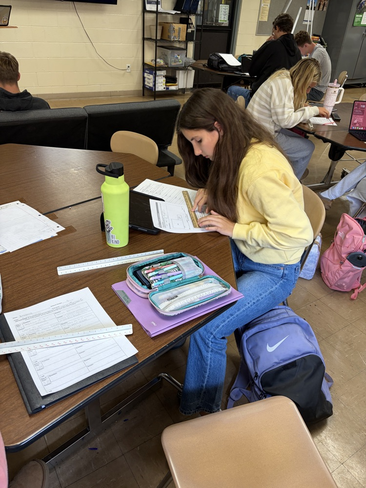 Student calculating facility size using scale measurements.