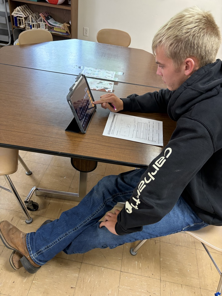 Student calculating facility size using scale measurements.