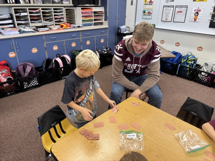 Kindergarteners and seniors together for Homecoming doing centers