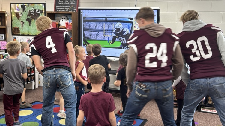 Kindergarteners and seniors together for Homecoming doing centers