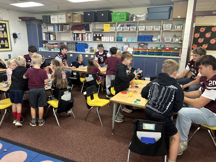Kindergarteners and seniors together for Homecoming doing centers