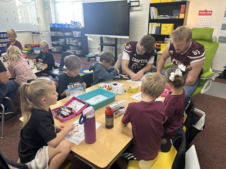Kindergarteners and seniors together for Homecoming doing centers