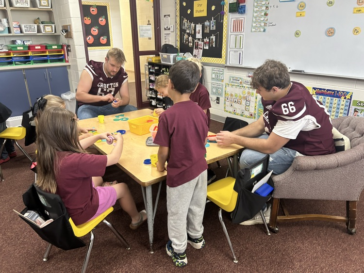 Kindergarteners and seniors together for Homecoming doing centers