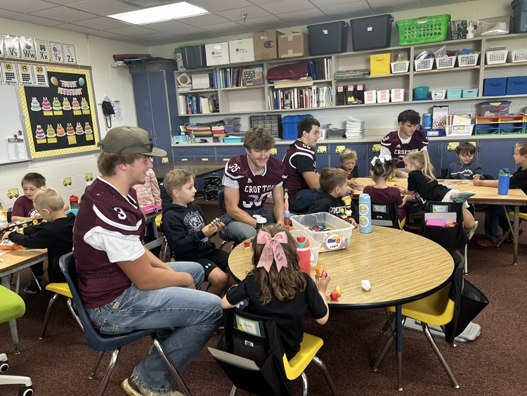 Kindergarteners and seniors together for Homecoming doing centers