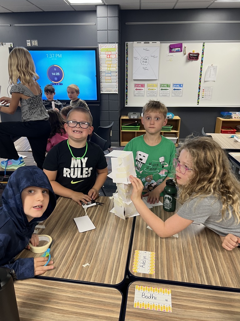 4 students at desks bulidng with index cards