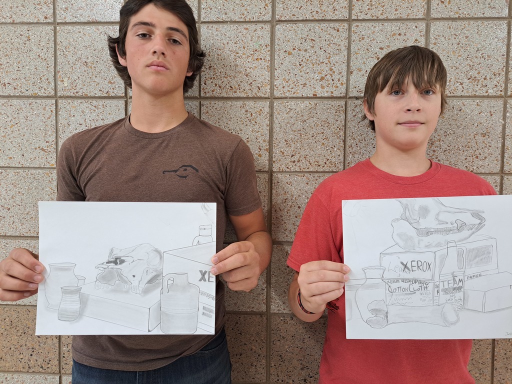 two males holding still life drawings