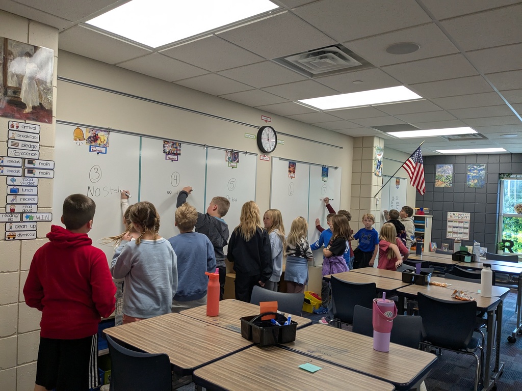students at marker boards writing numbers and words