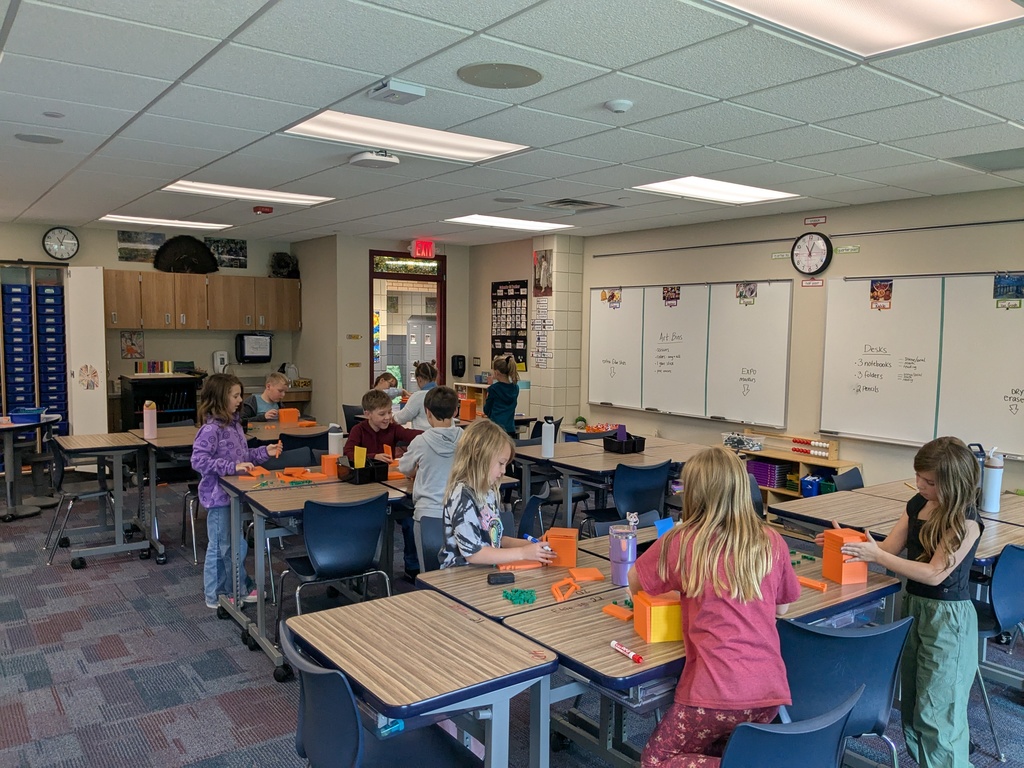 students at their desks building with orange blocks
