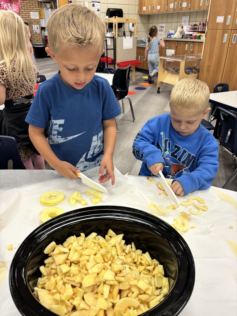 two male students cutting apples and putting in a crockpot