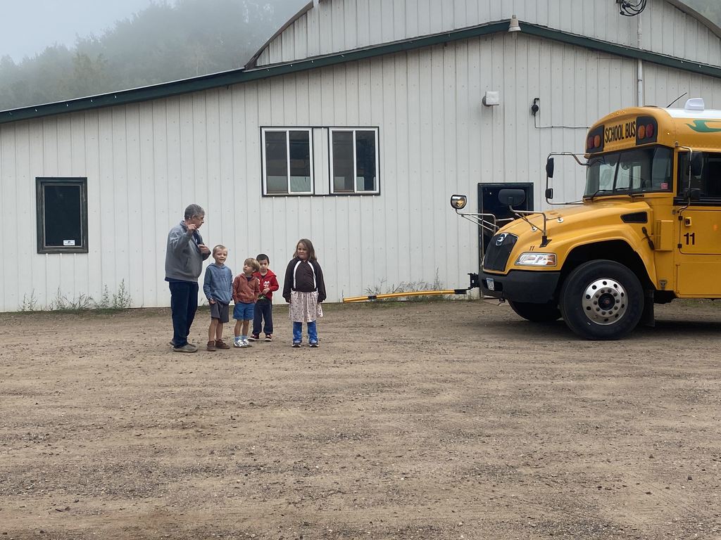 bus driver showing students how and when to cross in front of a bus