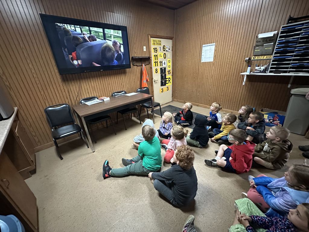 kindergartners sitting on the floor watching a bus safety 