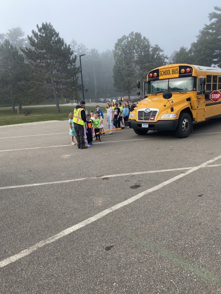 bus driver showing students how to properly walk in front of a bus
