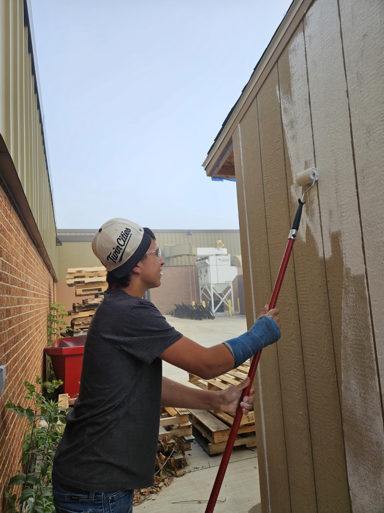 male student painting a shed