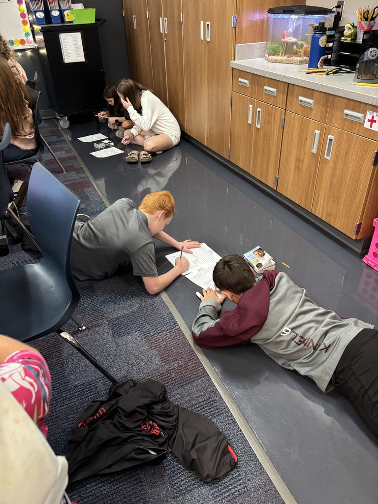 multiple students sitting on the floor working together on their ELA assignment