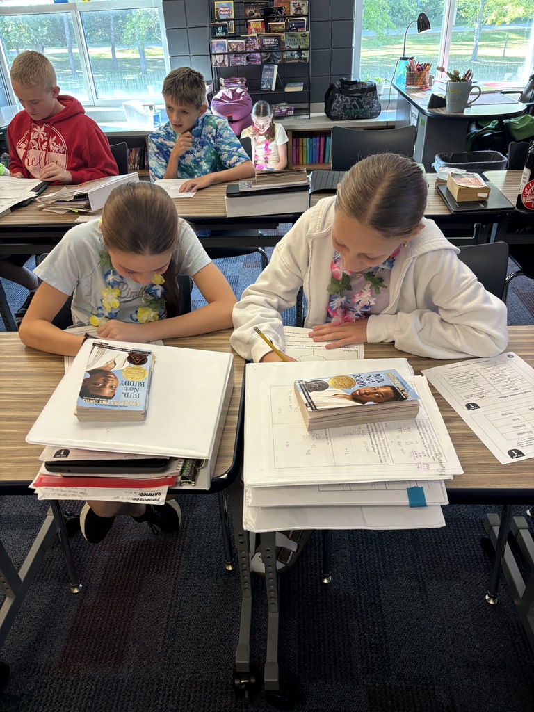 two female students working on their worksheets with stacks of books in front of them
