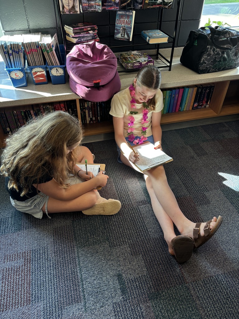 two females sitting on the floor working together on their worksheets