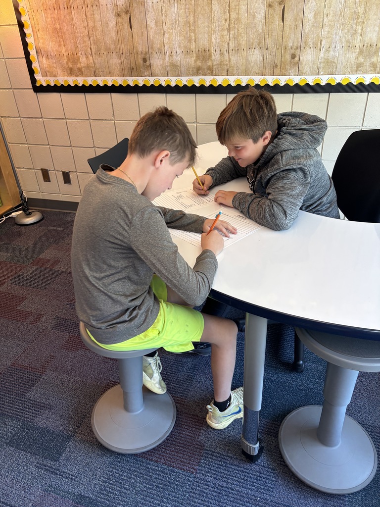 two males sitting face to face working on their worksheets