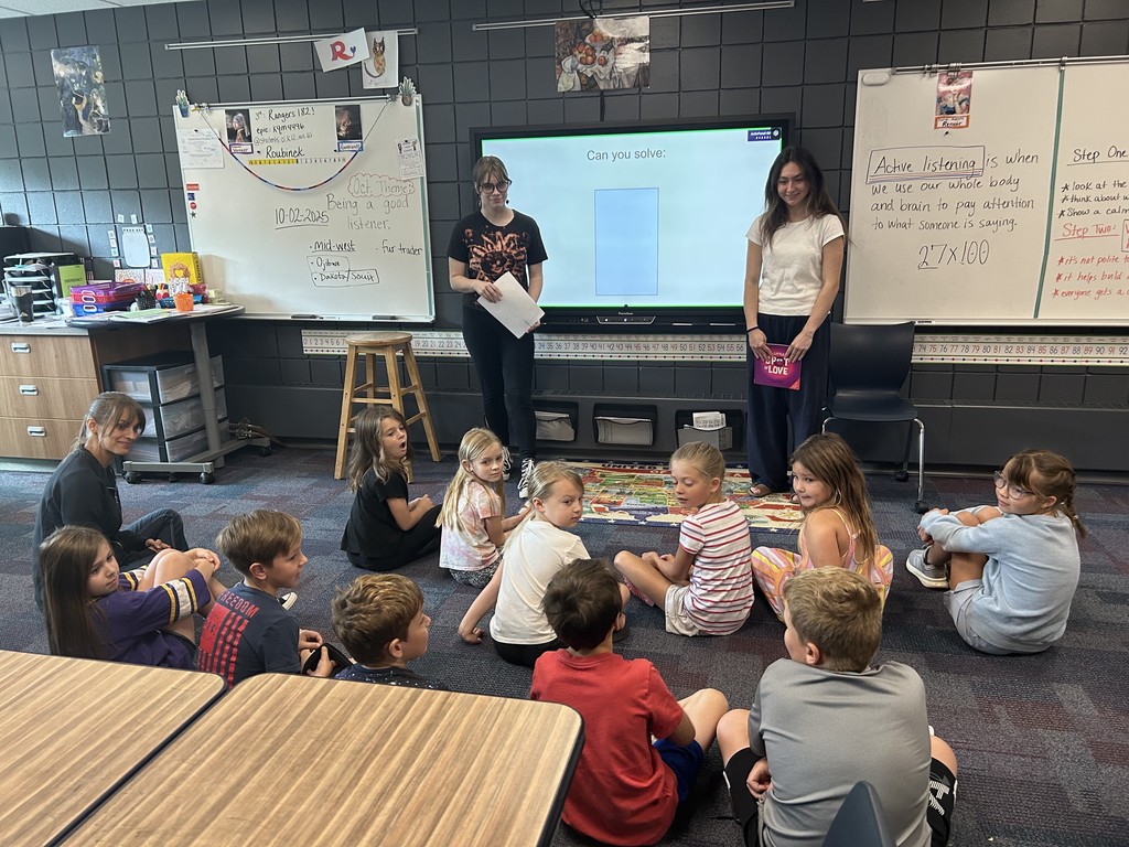 two high school females giving a lesson to younger students