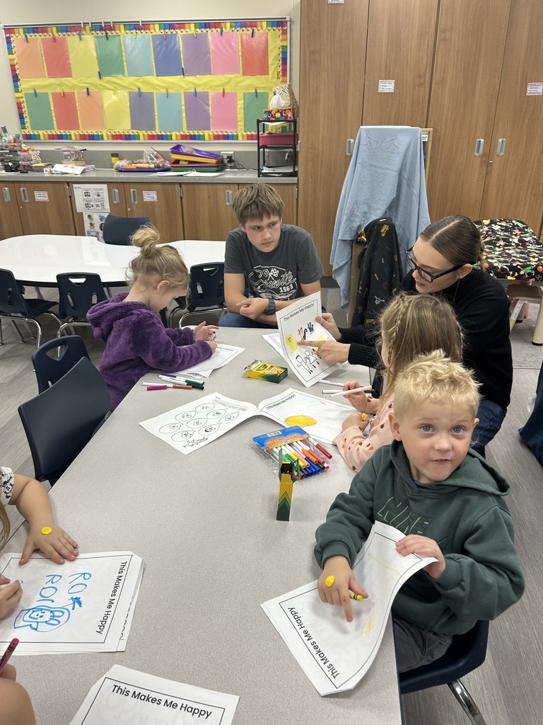 two older students working with younger students at a table