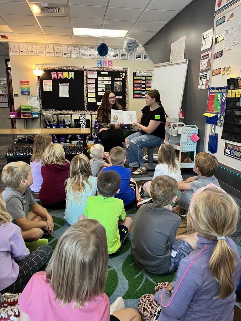 two female seniors reading a story to younger students