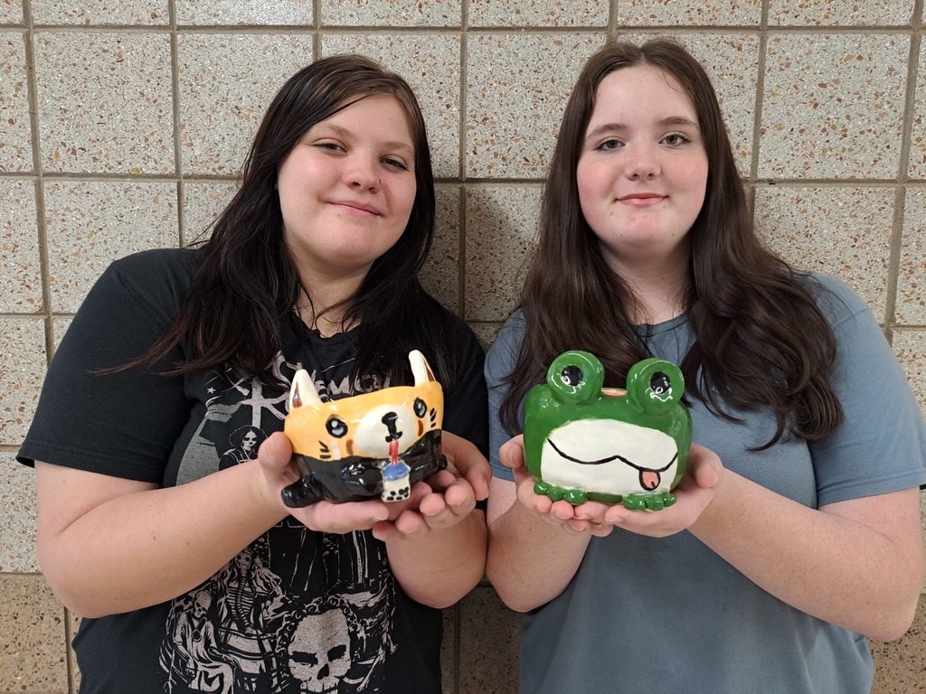 two female students holding pinch pot creatures they made in Art class
