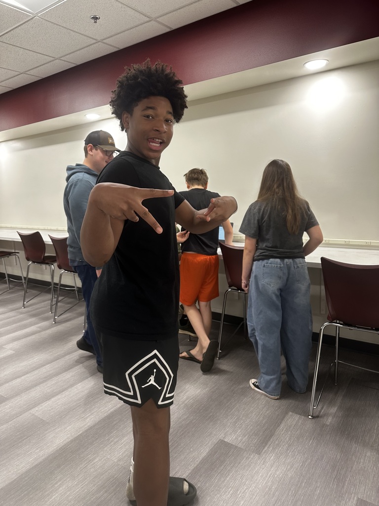 Student working together, one of them giving peace signs as they work on their video