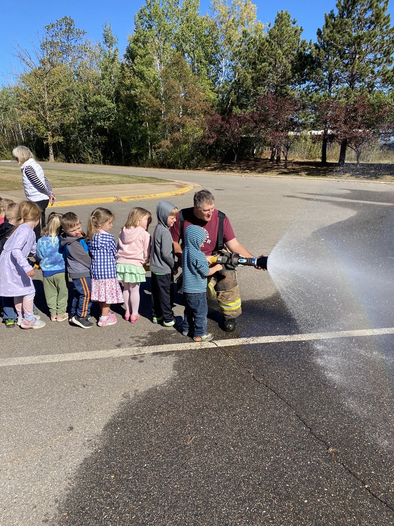 Fireman helping young students spray the big fire hose