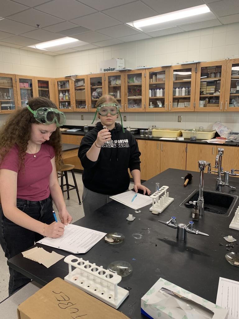 two females at working on their lab worksheets one of them holding something