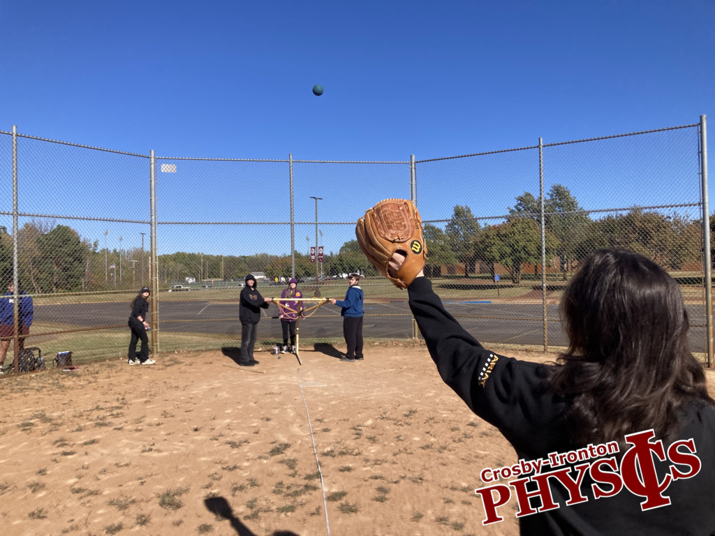 student holding a baseball glove ready to catch a ball from the homemade slingshot