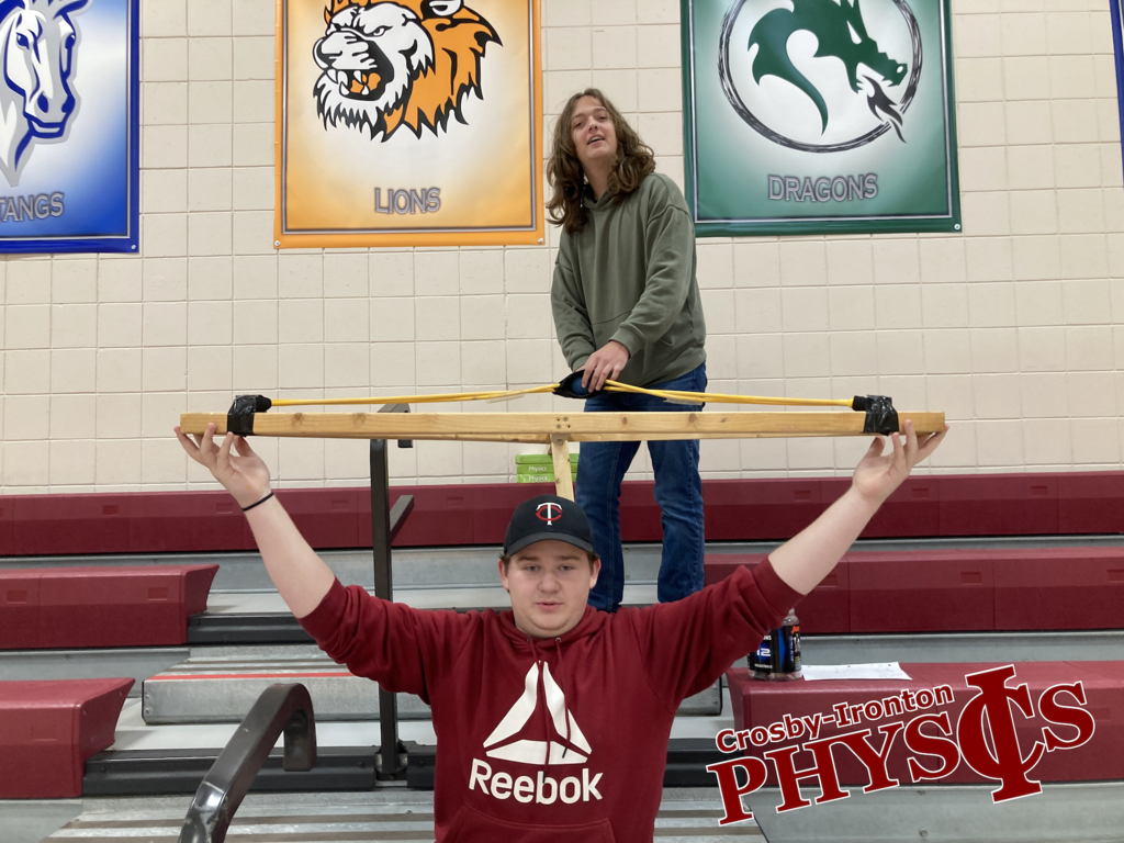 two students holding the homemade slingshot in Physics class