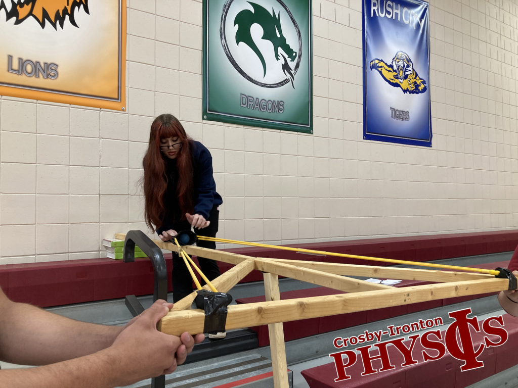 A student loading the homemade slingshot in Physics class