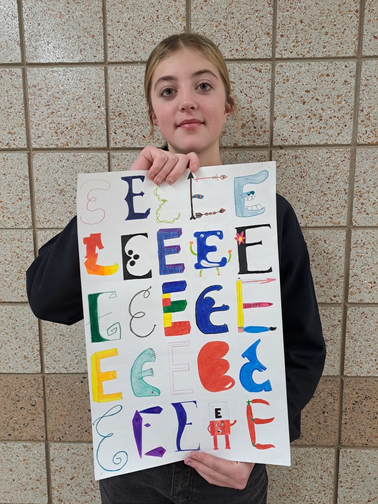 Female student holding 25 letter variations that she has drawn