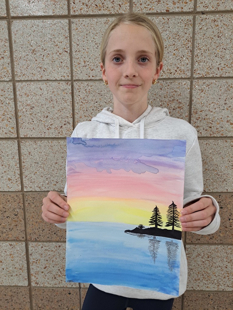 McKenna holding a water color painting of an island with trees and a sunset