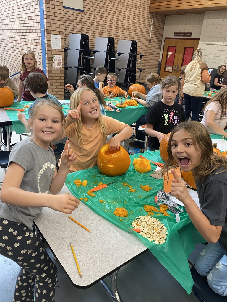 Three students gutting a pumpking and saving the seeds