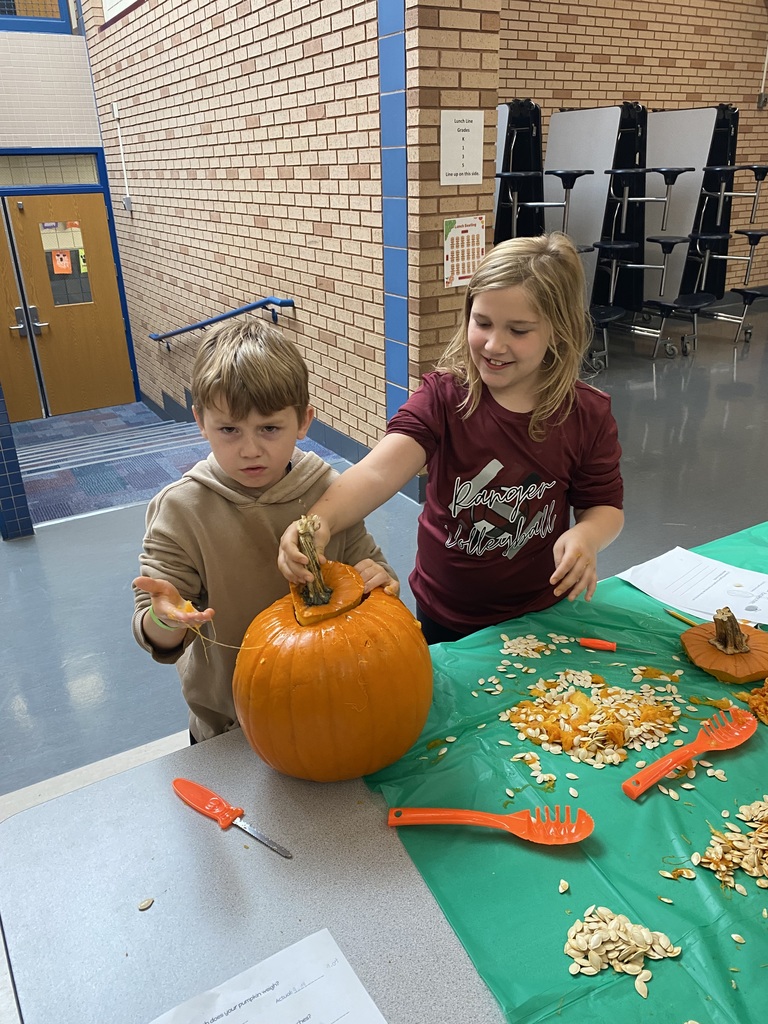 two students gutting a pumpkin with guts on their hands