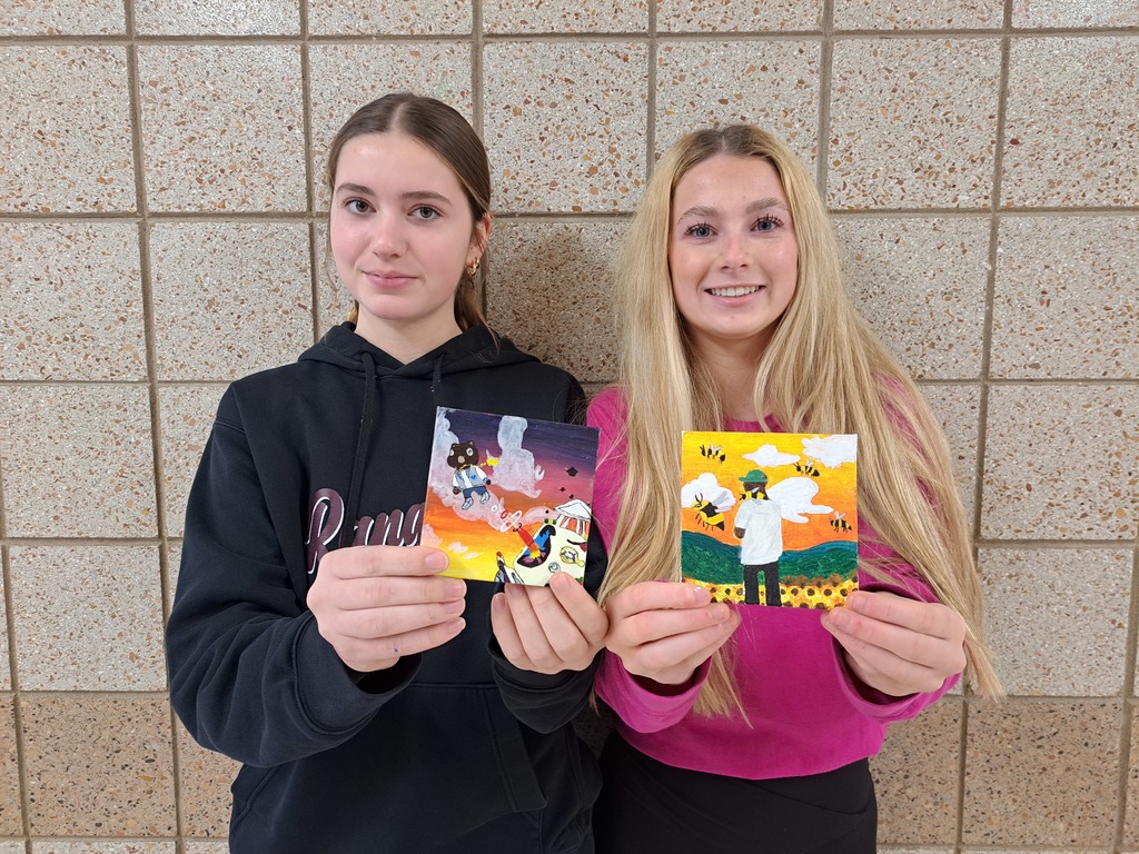 two female students holding their paintings of their album covers