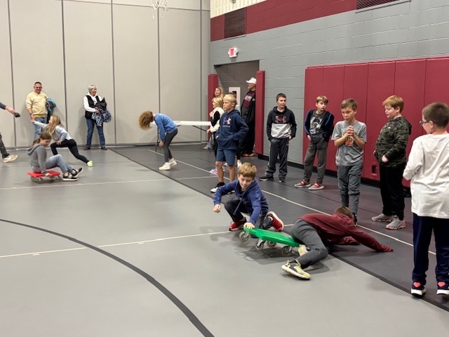 Students in the gym waiting for turns to ride the scooters to the other end and back