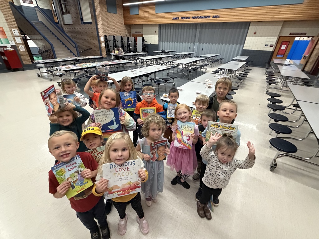A group young students holding and showing the book they received at Fall Into Reading Night