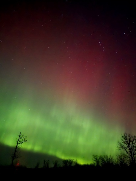 bright green northern lights dancing across the sky with pink higher up in the sky also showing stars