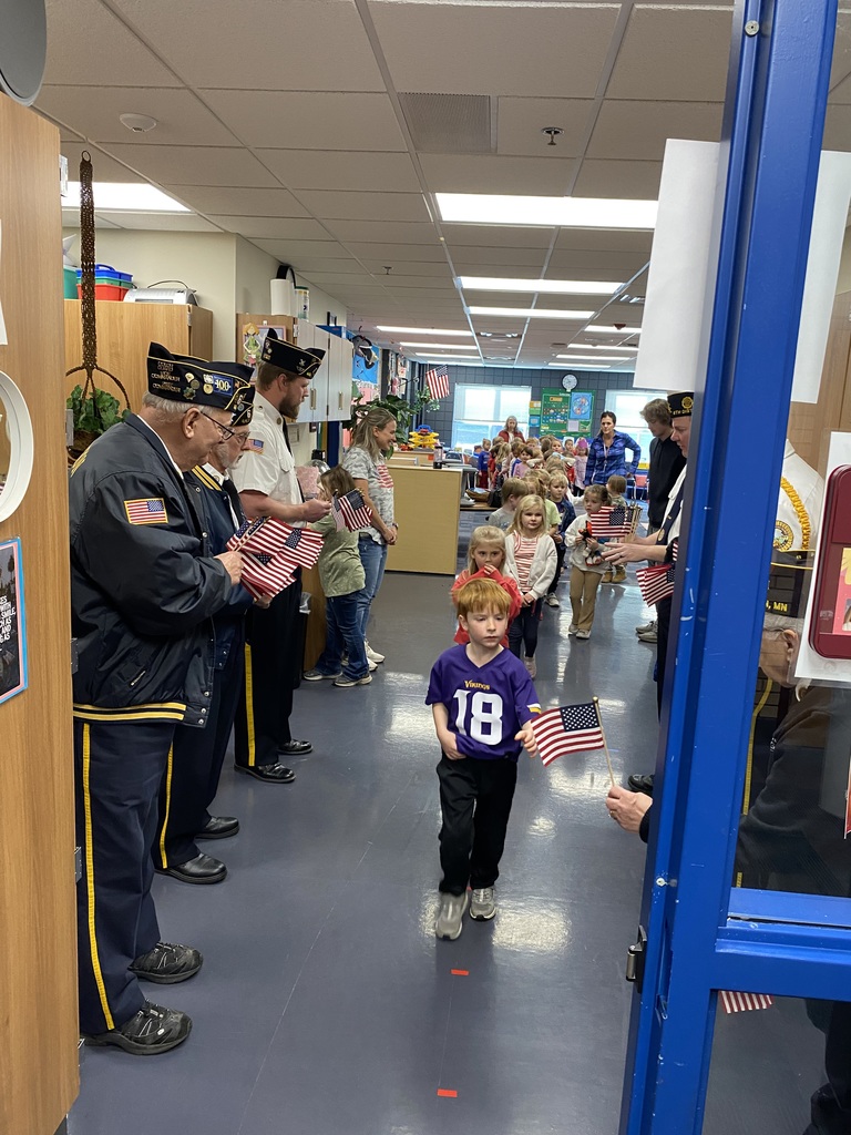 Kindergarteners walking out of their classroom and receiving an American flag from local veterans