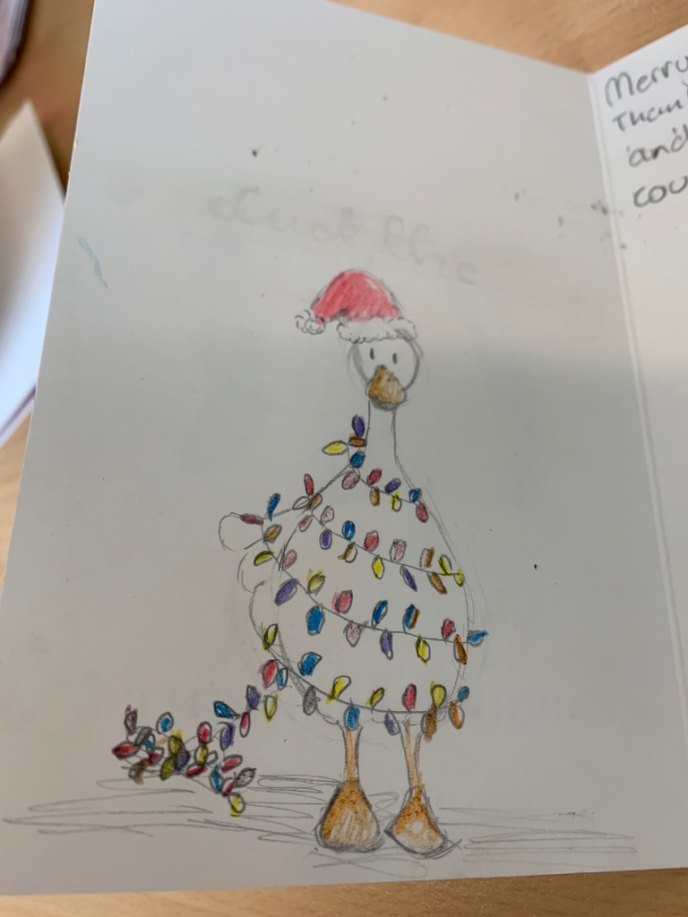 Hand drawn holiday card of a white goose wrapped up in holiday lights wearing a santa hat