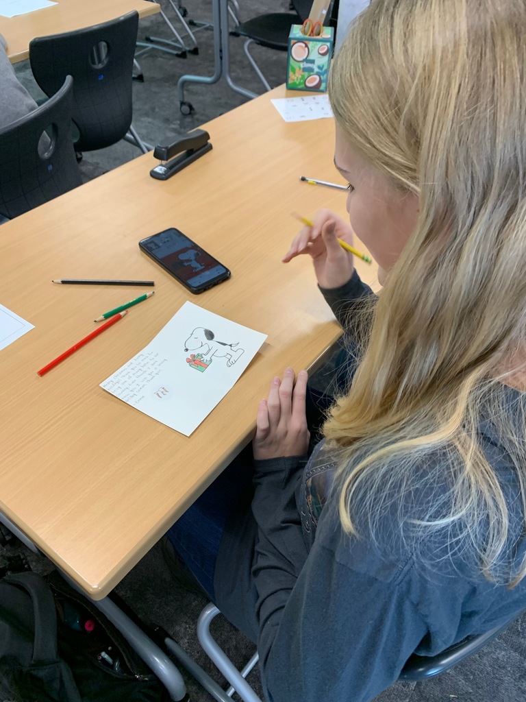 a student writing a message to someone in the military who will be receiving a holiday for heroes card