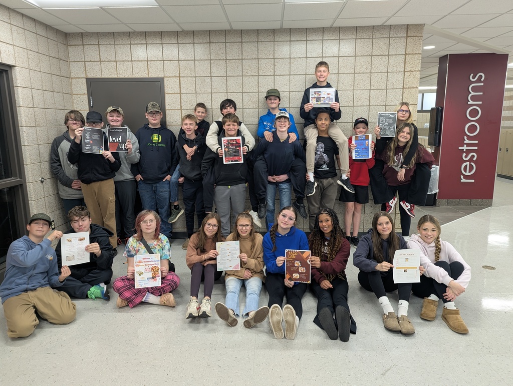 8th graders from English Class holding up their menus they created using grammar they have learned