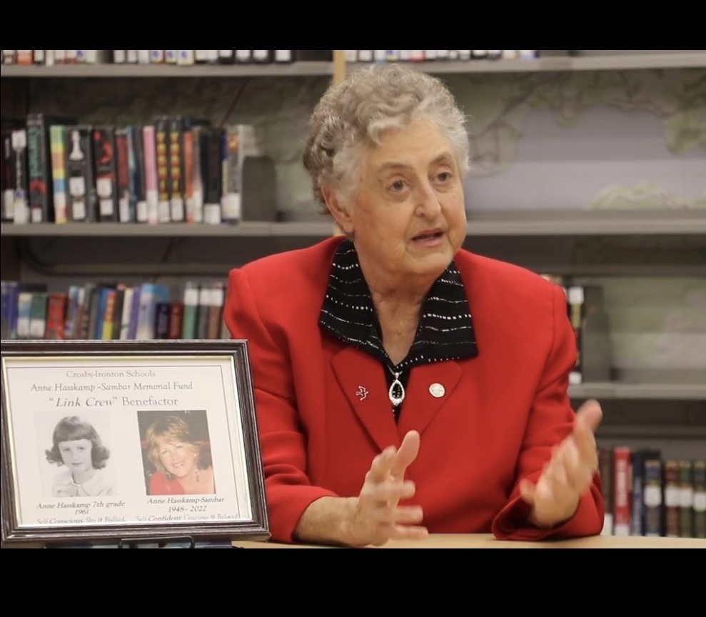 Kris Hasskamp sitting next to a photo of her sister, Anne.