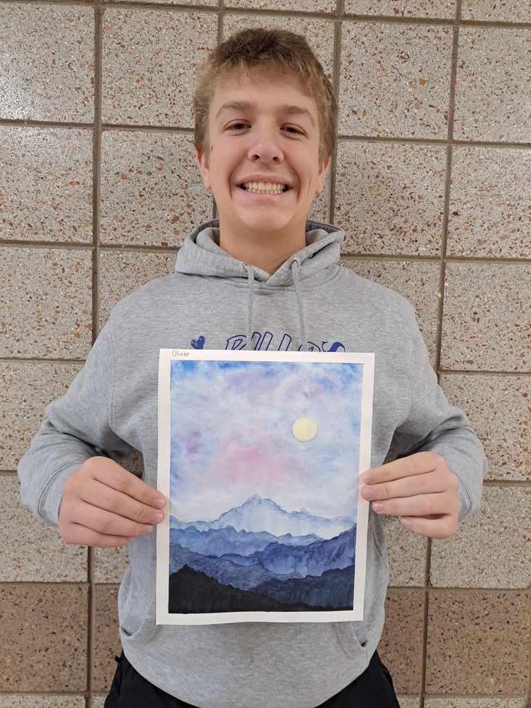 An 8th grade male student holding a watercolor painting of a blue-gray mountains with a moon and evening sky