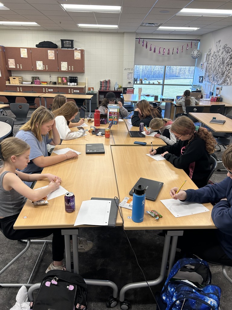 9 students sitting at tables during writing club