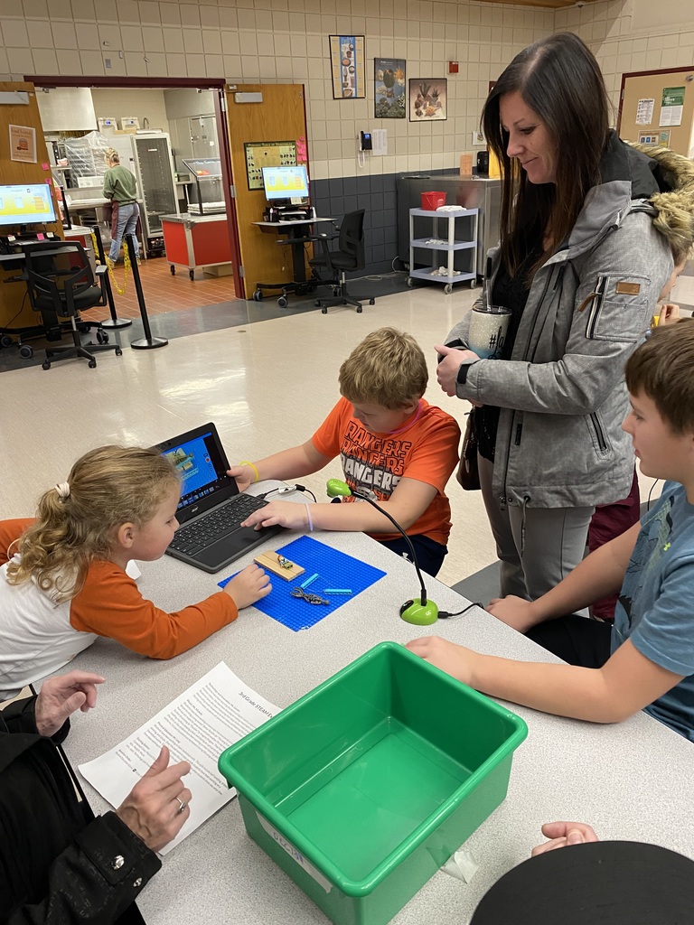 one male student showing his mom and other two siblings his editing software and the movie he made on his computer at the expo
