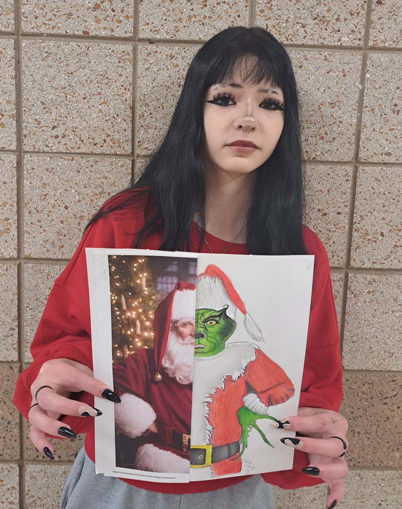 Female student holding a print out of santaon half  and a drawing of the Grinch on the other