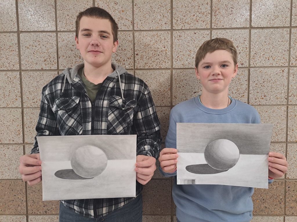two male students both holding a black and white pencil drawing of a 3d sphere